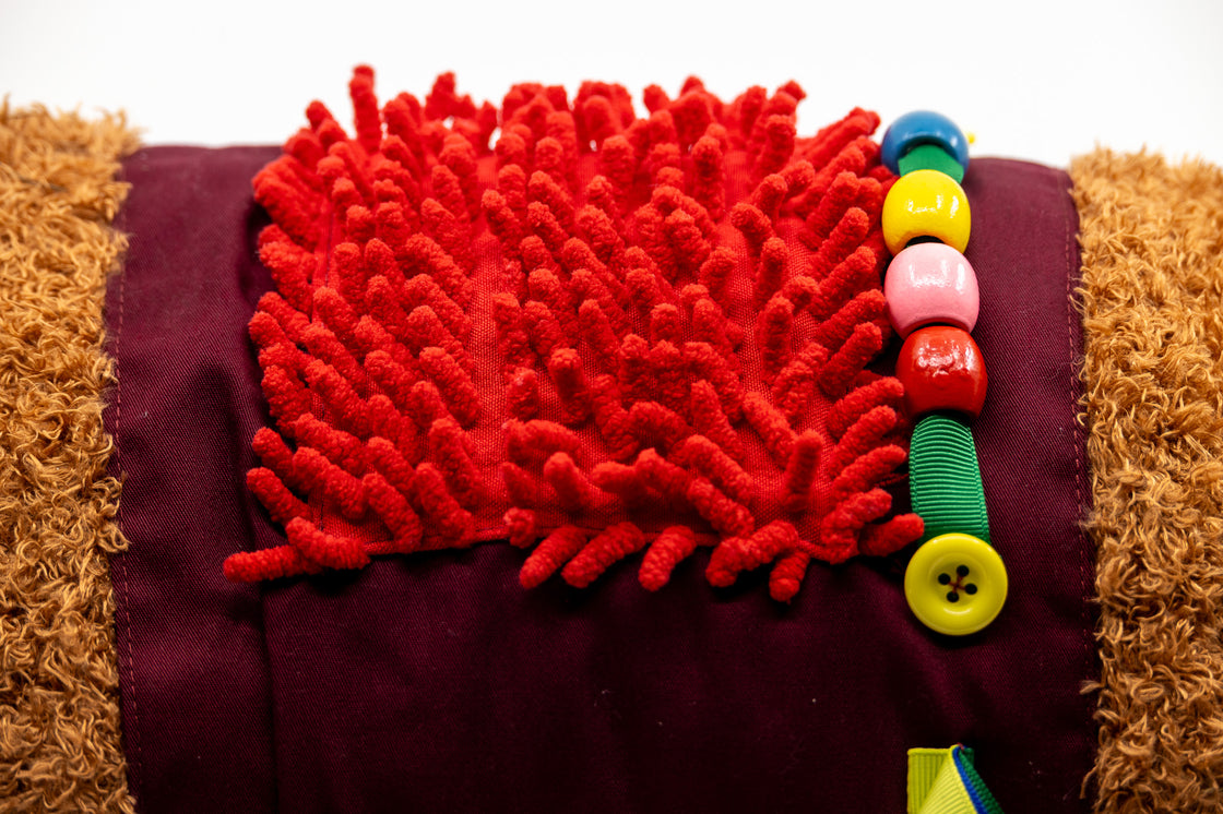 Rear view of sensory dog toy showing textured fabric and button details